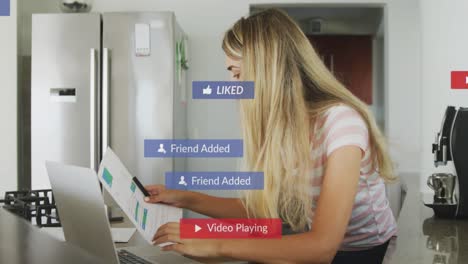 animation of social media notifications over woman working on laptop in kitchen