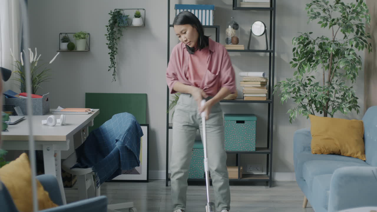 Young Woman Cleaning Her Living Room with a Wireless Vacuum