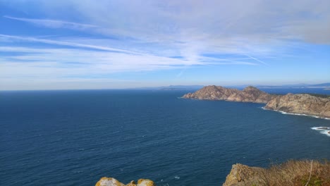 Unermesslichkeit-Des-Meeres-Mit-Den-Felsigen-Berginseln-Mit-Restwolken-Bis-Zum-Horizont-An-Einem-Sonnigen-Sommertag,-Rechts-Abbiegende-Panoramische-Aufnahme,-Cíes-inseln,-Pontevedra,-Galizien,-Spanien