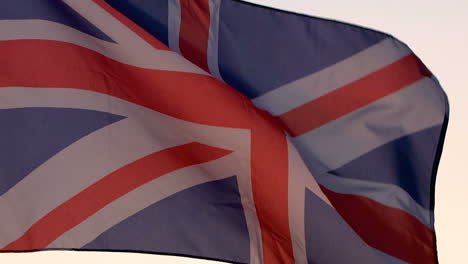 la bandera británica ondeando sobre el cielo al atardecer.