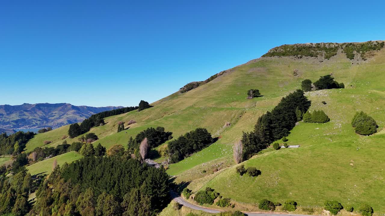Aerial animation reveals lush green hills and valleys under a clear blue sky, transitioning smoothly from a plane window view