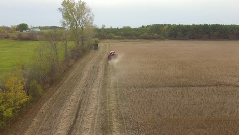 drones vuelan sobre árboles revelando tierras agrícolas con máquinas trabajando en la temporada de cosecha