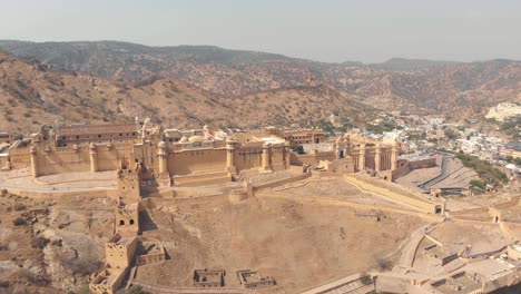 Glorious-Amber-Fort-standing-on-terraced-plateau-of-a-barren-mountain-in-Jaipur,-Rajasthan,-India---Aerial-wide-orbit-panoramic-shot