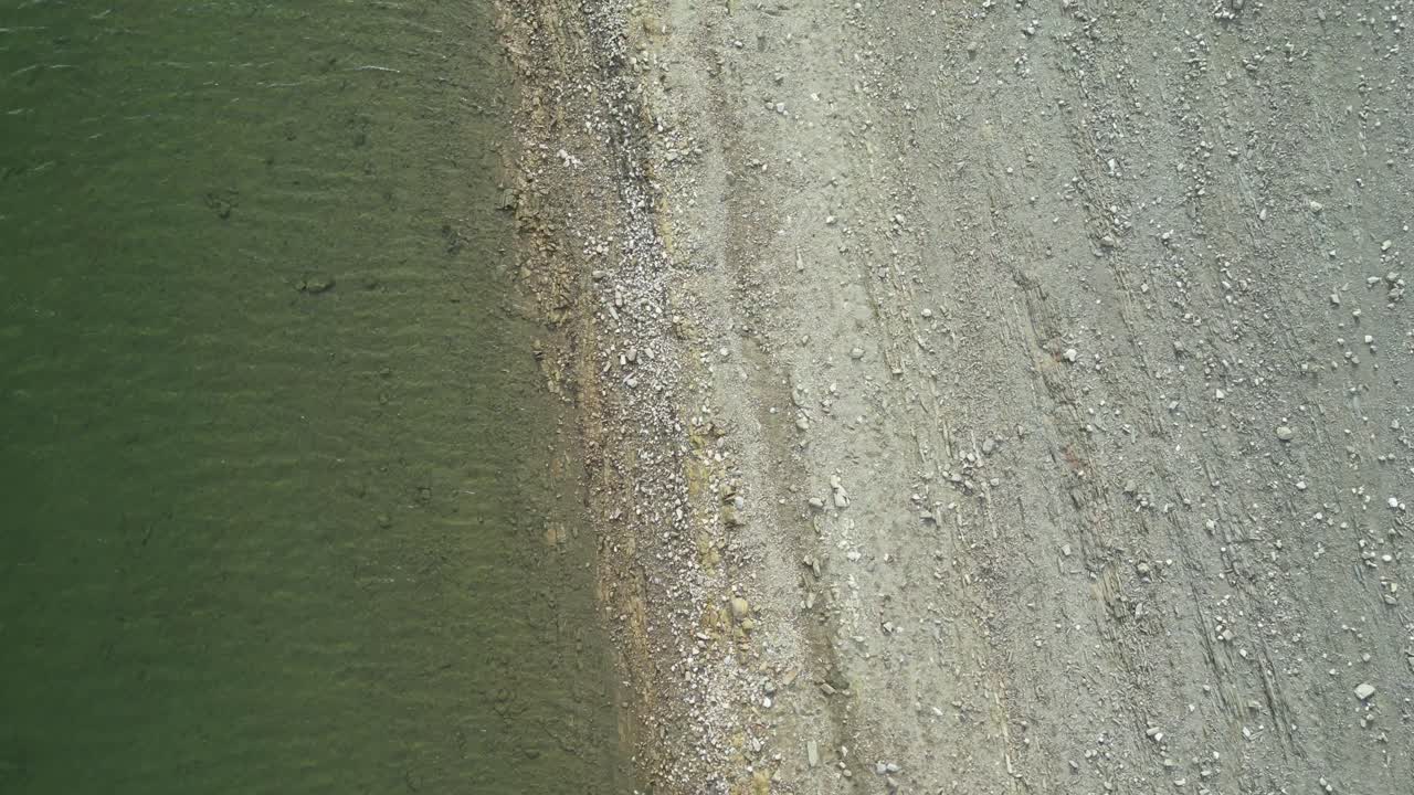 Drone view of the water’s edge of a reservoir with shore line with stones.