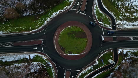 cars driving on roundabout in early winter season, aerial top down view