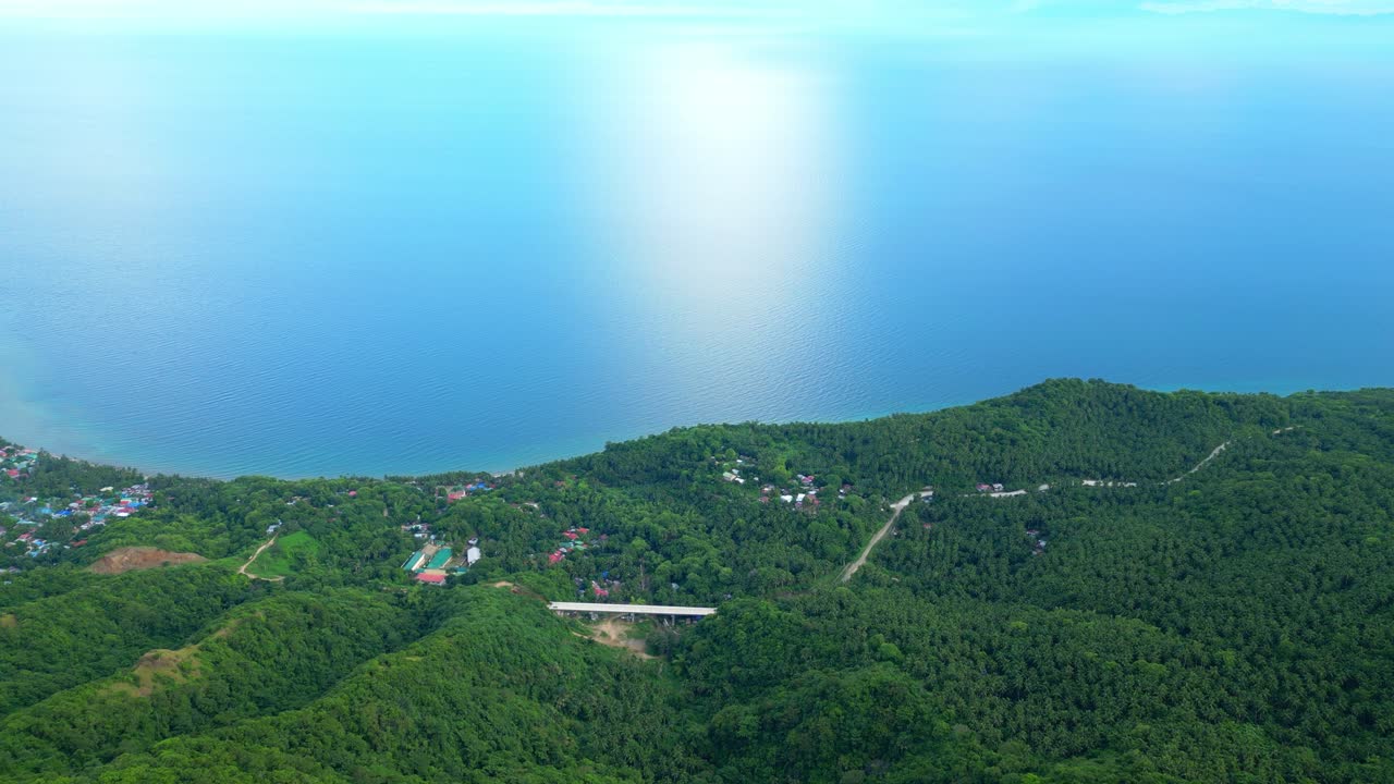 ロボ（バタンガス州）の広大な熱帯植物の空撮から、タヤバス湾のきらめく青い海岸線へと移行するハイアングルでの撮影。