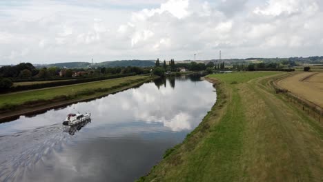 aerial footage follows a river boat gently sailing across the river trent in nottinghamshire