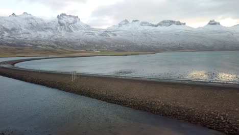 Panoramic-winter-footage-of-road-leading-along-coast-of-sea-to-volcanic-mountains