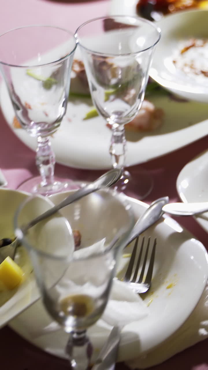Residue of foodstuffs in the white plastic dish on wooden table. Finished with dinner Vertical video