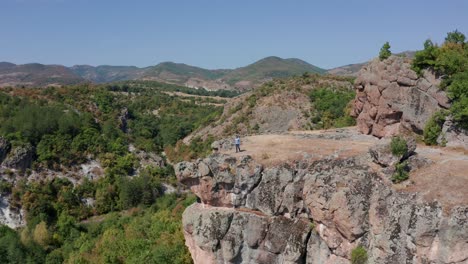 Man-Walking-To-The-Edge-Of-Cliff-At-Harman-Kaya-Rock-Sanctuary-In-Rhodope-Mountain,-Bulgaria