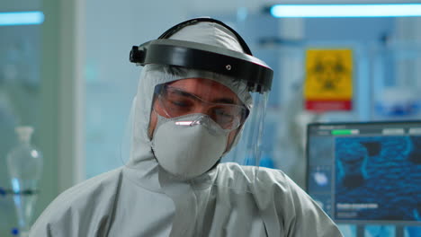 close up of tired chemist man doctor in coverall working in lab