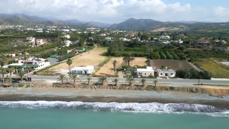 Chrysochous-bay-with-coastline,-clear-waters,-and-rural-landscape,-sunny-day,-aerial-view