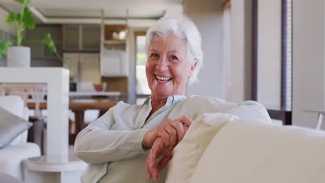 Retrato-De-Una-Mujer-Caucásica-Mayor-Sonriendo-Mientras-Se-Sienta-En-El-Sofá-En-Casa