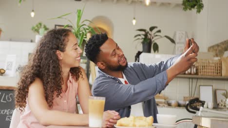 Feliz-Pareja-Diversa-Pasando-Tiempo-Juntos-En-La-Cafetería,-Tomando-Café-Y-Tomándose-Selfie