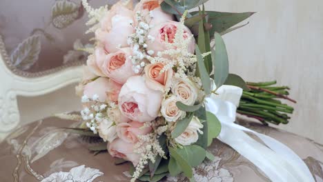 beautiful wedding bouquet with pink flowers lying on the chair in the room