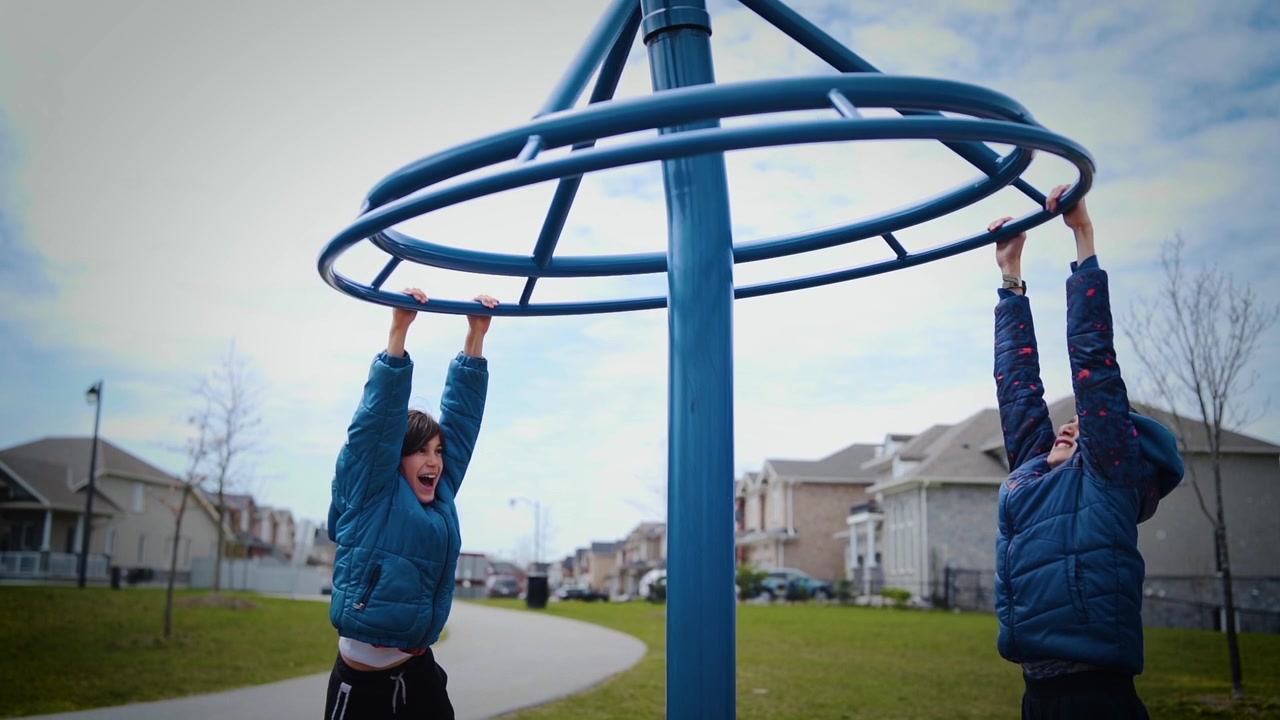 Two boys spinning around and having fun in a park