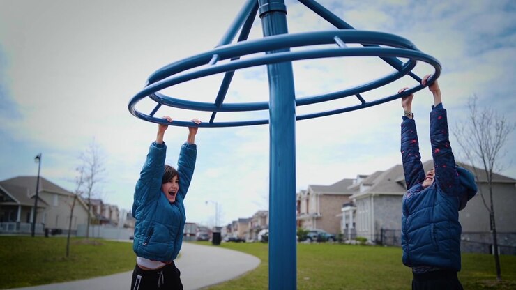 Two boys spinning around and having fun in a park