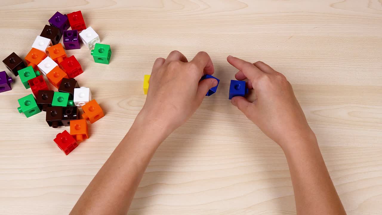 Hands assembling colorful linking cubes on table