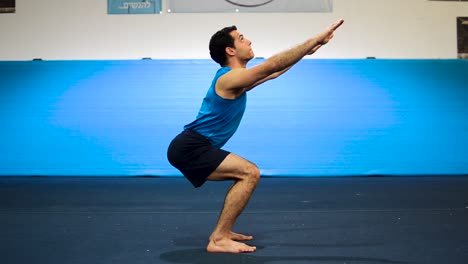 a still shot of a guy doing squats in a gymnastics gym