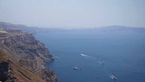 Weite-Aufnahme-Von-Klippen-In-Santorini-Griechenland-Aus-Der-Ansicht-Oben-Auf-Die-Stadt-Thira-Mit-Booten,-Inseln-Im-Hintergrund