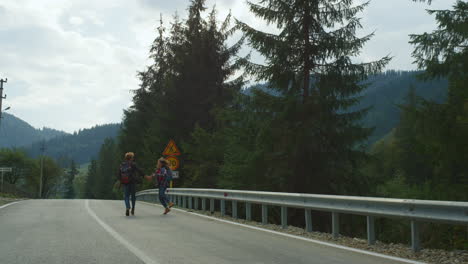 Hikers-couple-jumping-road-in-mountains-forest.-Positive-lovers-enjoy-honeymoon.