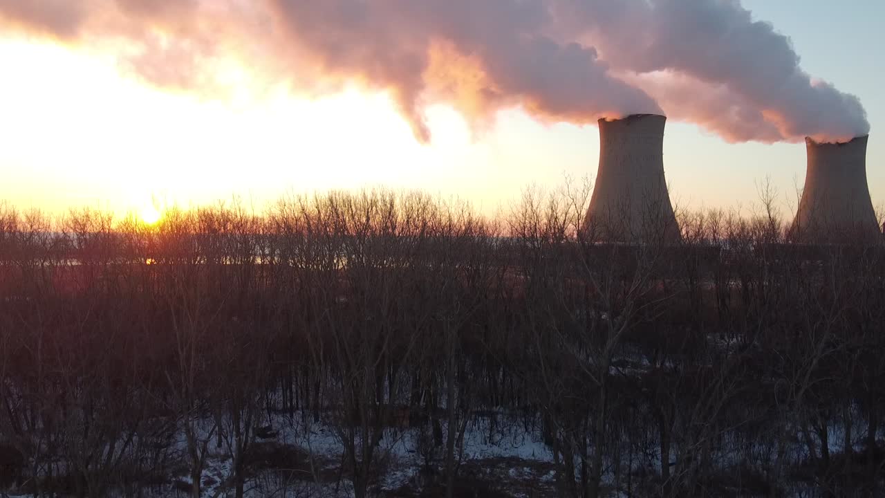dolly up toma aérea de drones de las torres de enfriamiento de la planta de energía nuclear al amanecer atardecer con vapor y humo sol brillante invierno