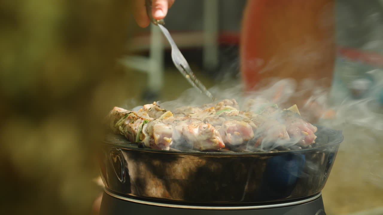 Uomo che cucina spiedini al barbecue in campeggio. Di giorno, Francia.