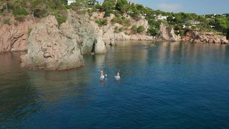 Fit-women-floating-on-paddle-board-in-sea