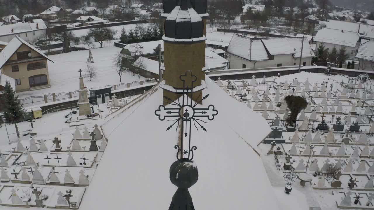 큰 교회와 묘지에 초점을 맞춘 산맥 아래 계곡에 있는 눈 덮힌 마을의 드론 보기