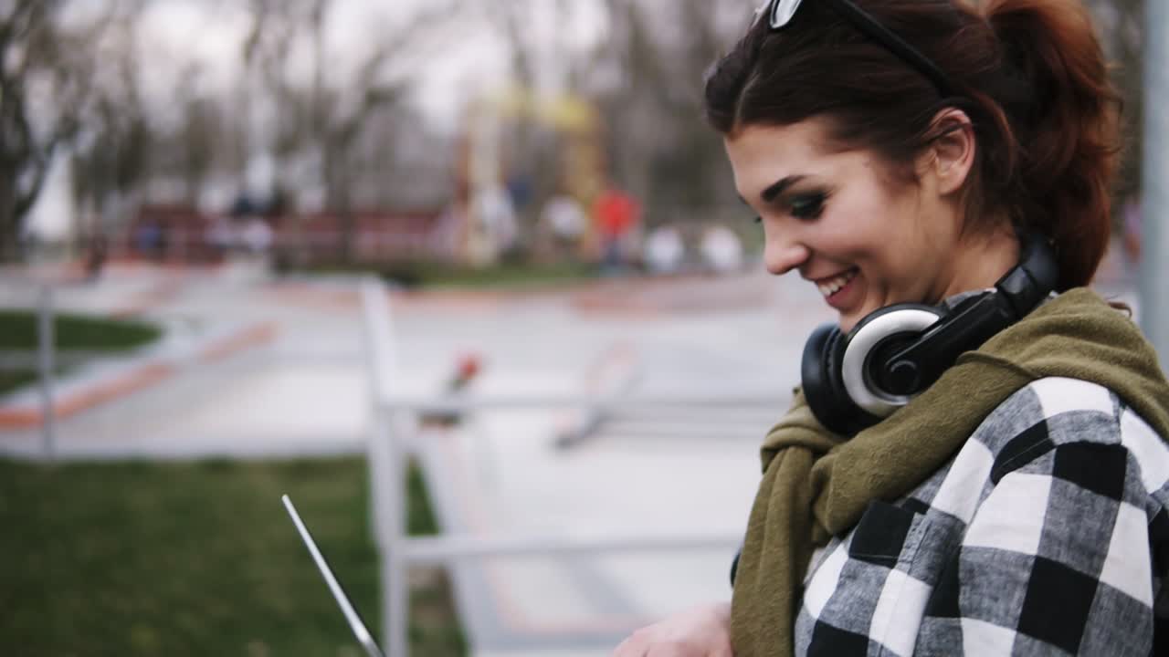 joven alegre con una computadora portátil en sus manos caminando por el parque y escribiendo al mismo tiempo. riendo y divirtiéndose. fondo borroso