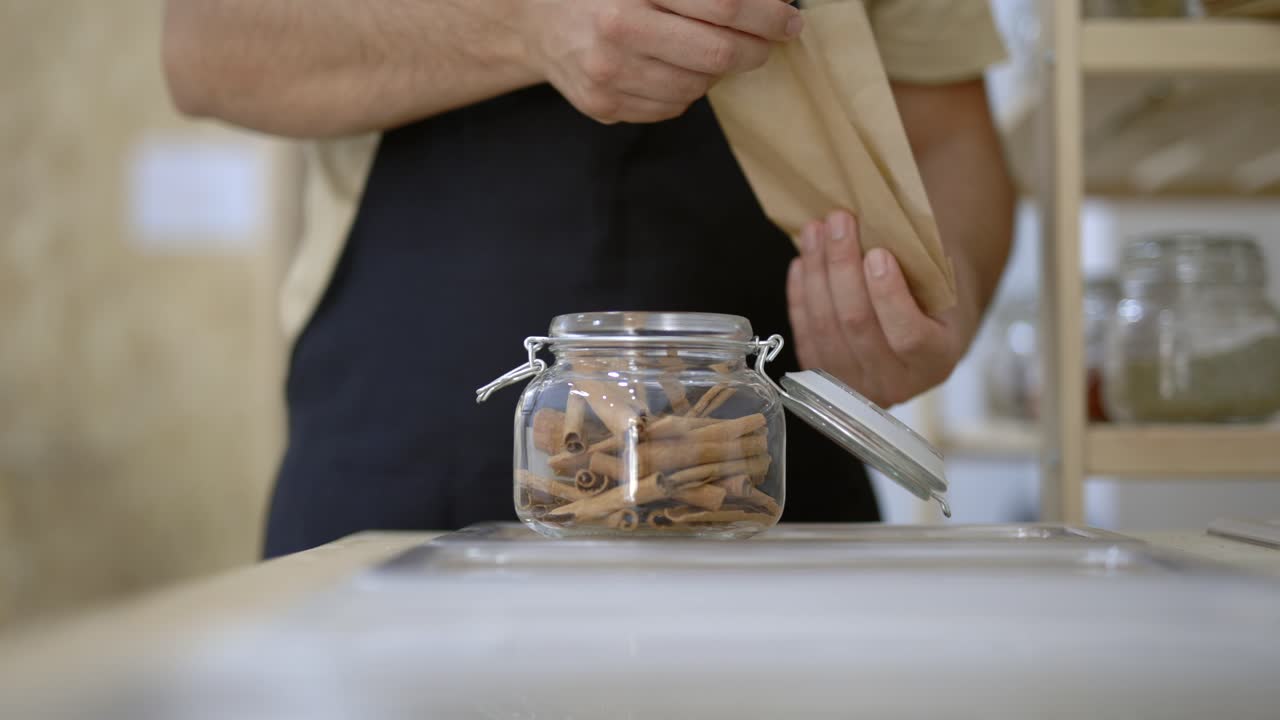 comerciante llenando una bolsa de papel con palitos de canela