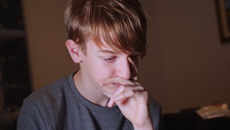 teenager boy with pimples on his face who is thinking with his hand resting on his chin