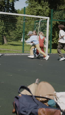 children playing soccer on a green field with backpacks in the foreground