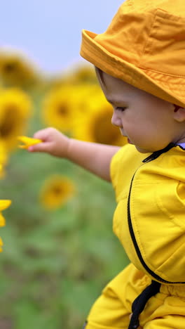 baby in yellow outfit playing in a sunflower field
