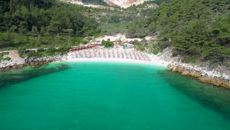 circular aerial view revealing a white beach with turquoise water and lush green vegetation, marble beach, thassos island, greece