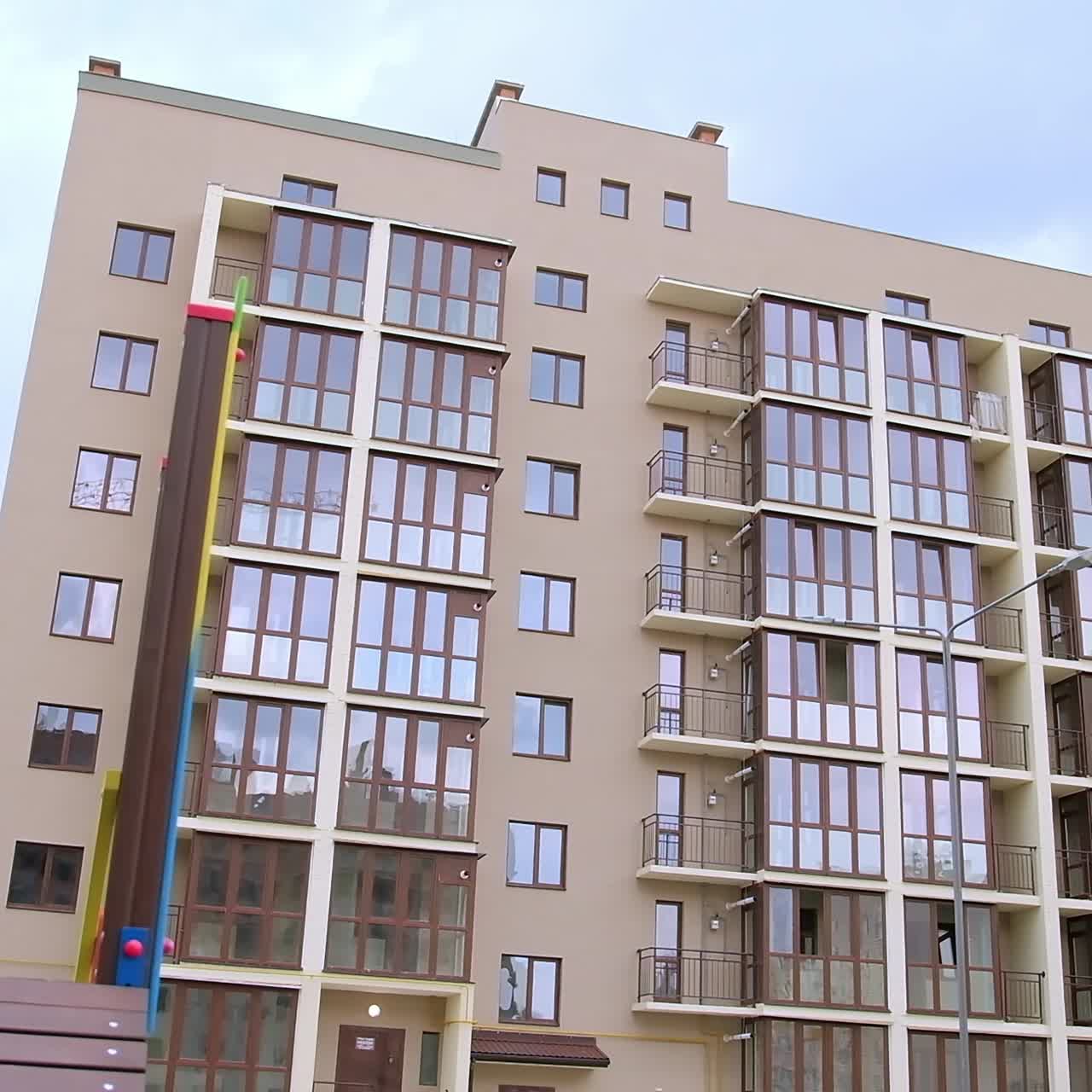 Good-looking exterior of the new recently constructed block of flats. Colorful playground nearby the residential house