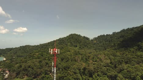 aerial shot of telecommunications tower on a tropical island with jungle and ocean