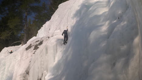 Wide-angle-view-of-a-climber-ascending-a-the-summit-of-a-wall-of-frozen-ice