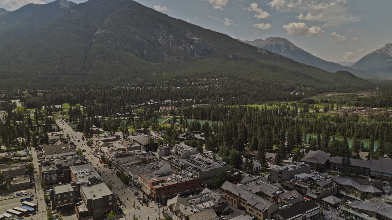 banff ab canada aerial v35 drone flyover centro de la ciudad a través del río bow alimentado por el glaciar capturando el pintoresco paisaje de la ciudad y el paisaje de las cadenas montañosas en verano - filmado con mavic 3 pro cine - julio 2023