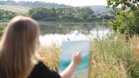 artist painting a landscape by a lake