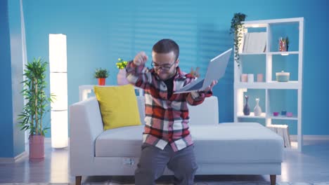 Dwarf-young-man-standing-at-home-looking-at-laptop-screen-feeling-excited-and-dancing