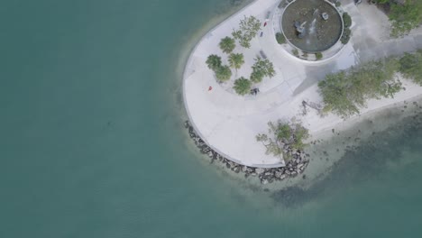 una vista cautivadora a vista de pájaro: una mujer y un pájaro se levantan de las aguas cristalinas en una península soleada