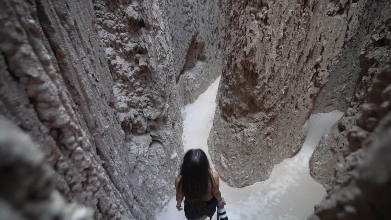 mujer joven con cámara de fotos caminando en el cañón de ranura surrealista en el parque estatal de la garganta de la catedral, nevada, ee.uu.