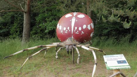 large model of garden spider with green trees on the background in kashubian park of giants, strysza buda, poland