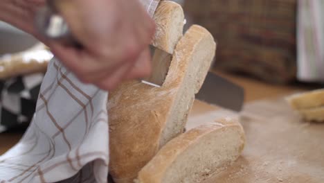 una rebanada de pan blanco cortada de una hogaza de pan con un cuchillo en una tabla de cortar de madera mientras otra rebanada de pan está al lado