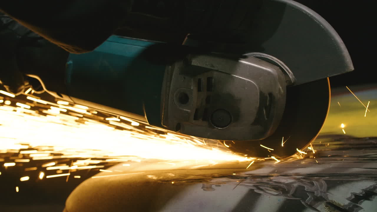 Close up of power tool grinder rotating blade creating spark on car surface