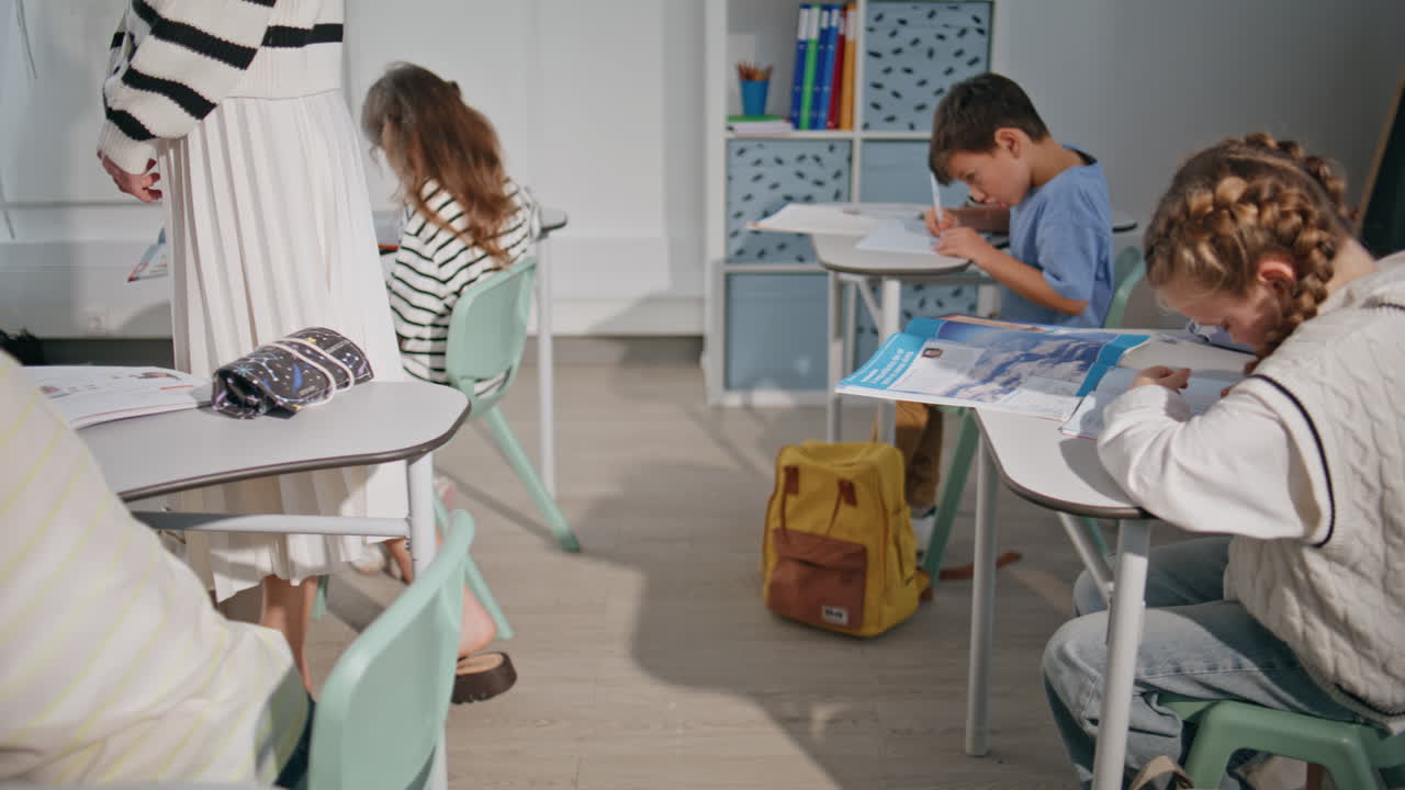 Unknown schoolteacher walking classroom with students closeup. Pupils doing test