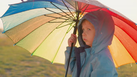 child stands alone in field on rainy day each droplet on umbrella serves as reminder of unsettled