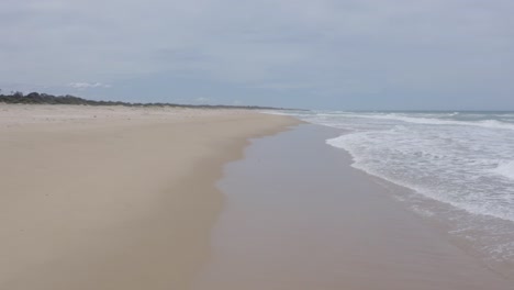 Primer-Plano-De-Seguimiento,-Vuelo-De-Drones-Sobre-Las-Olas-En-La-Costa-Australiana,-Olas-Rompiendo-En-La-Playa,-Nadie,-Luz-Del-Día