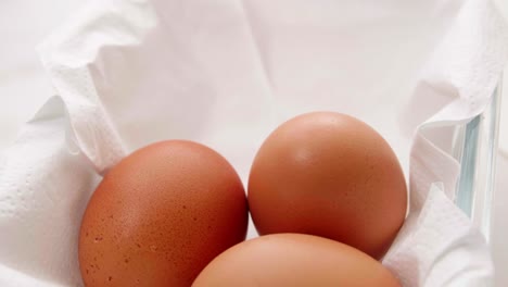 drei frische bio-eier in einem rotierenden behälter auf weißem packpapier zur lebensmittelzubereitung